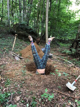 Person macht einen Handstand in einem Bodenprofil im Wald